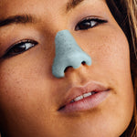 Load image into Gallery viewer, Young woman wearing reef-safe, cruelty-free, neon pastel blue Noz sunscreen on her face

